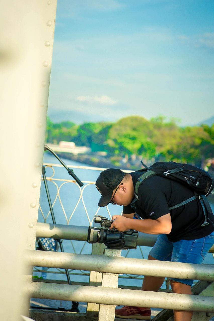 Camera operator filming behind-the-scenes footage on a busy production set